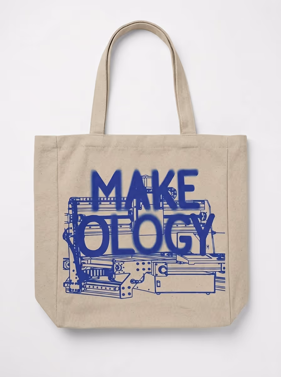 Beige tote bag with blue technical drawing and blue text reading MAKE OLOGY.