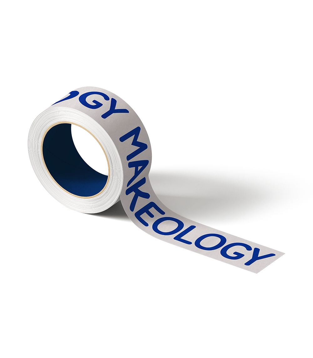 Roll of white tape with blue text reading MAKEOLOGY on a gray surface.
