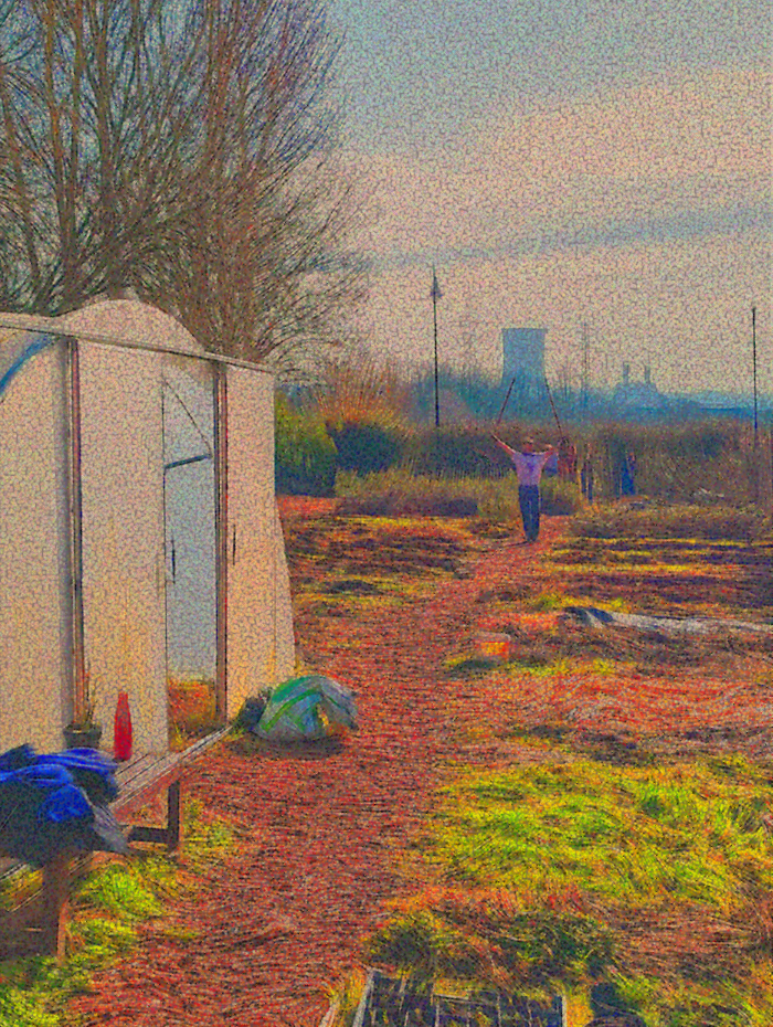 Person walking on dirt path near white structure with trees and industrial cooling towers in the background.